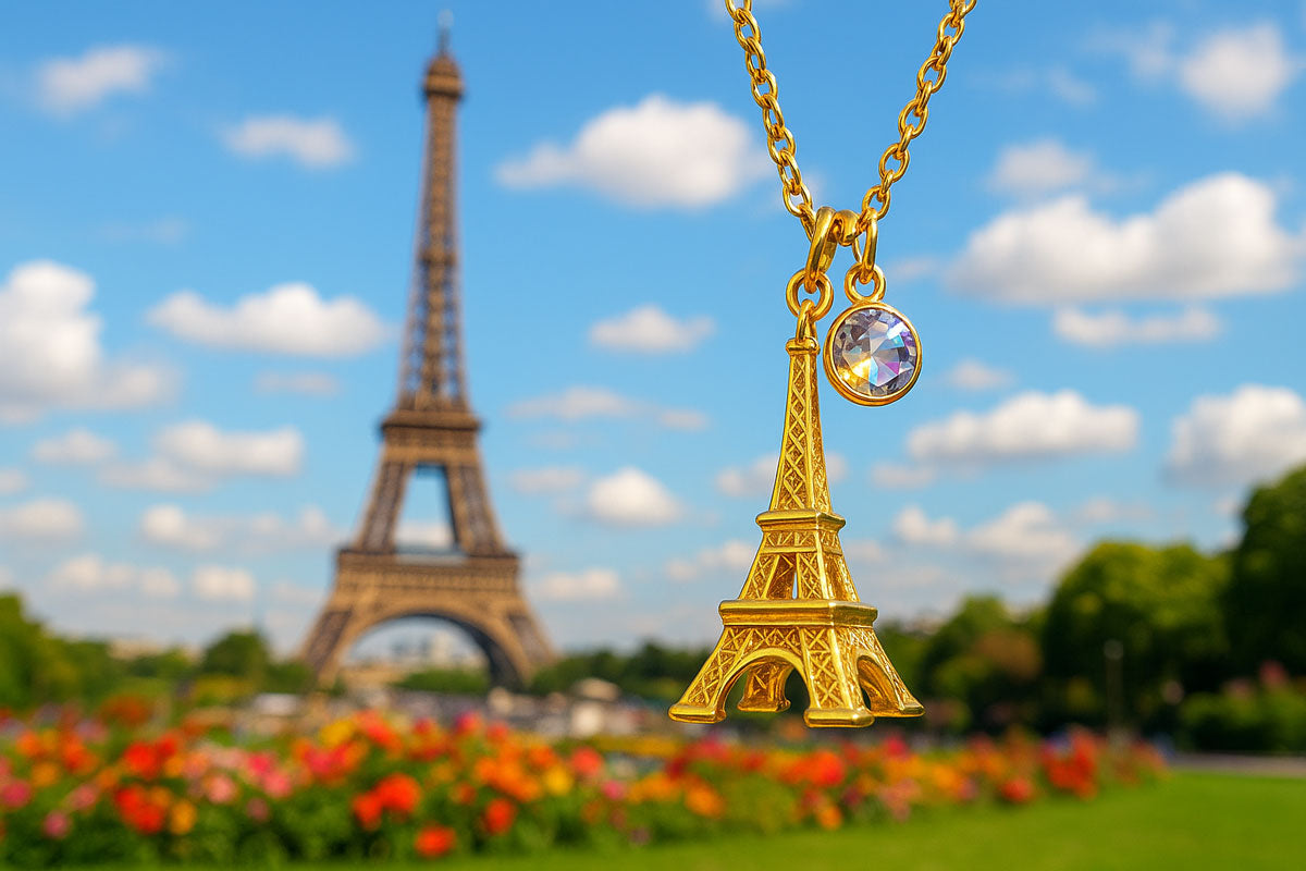 Collier pendentif doré Tour Eiffel avec cristal brillant, photographié devant la véritable Tour Eiffel à Paris, bijou fantaisie emblématique.